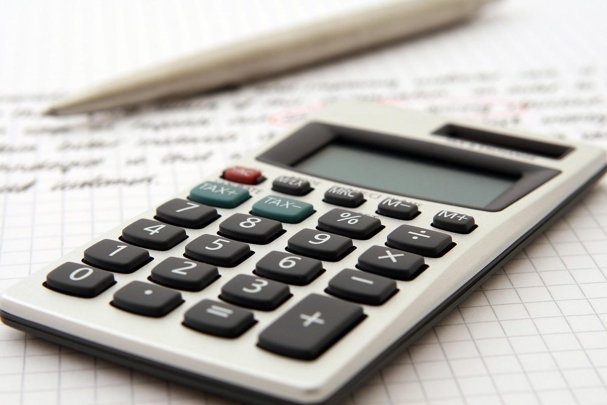Calculatrice et stylo posés sur des documents comptables manuscrits
