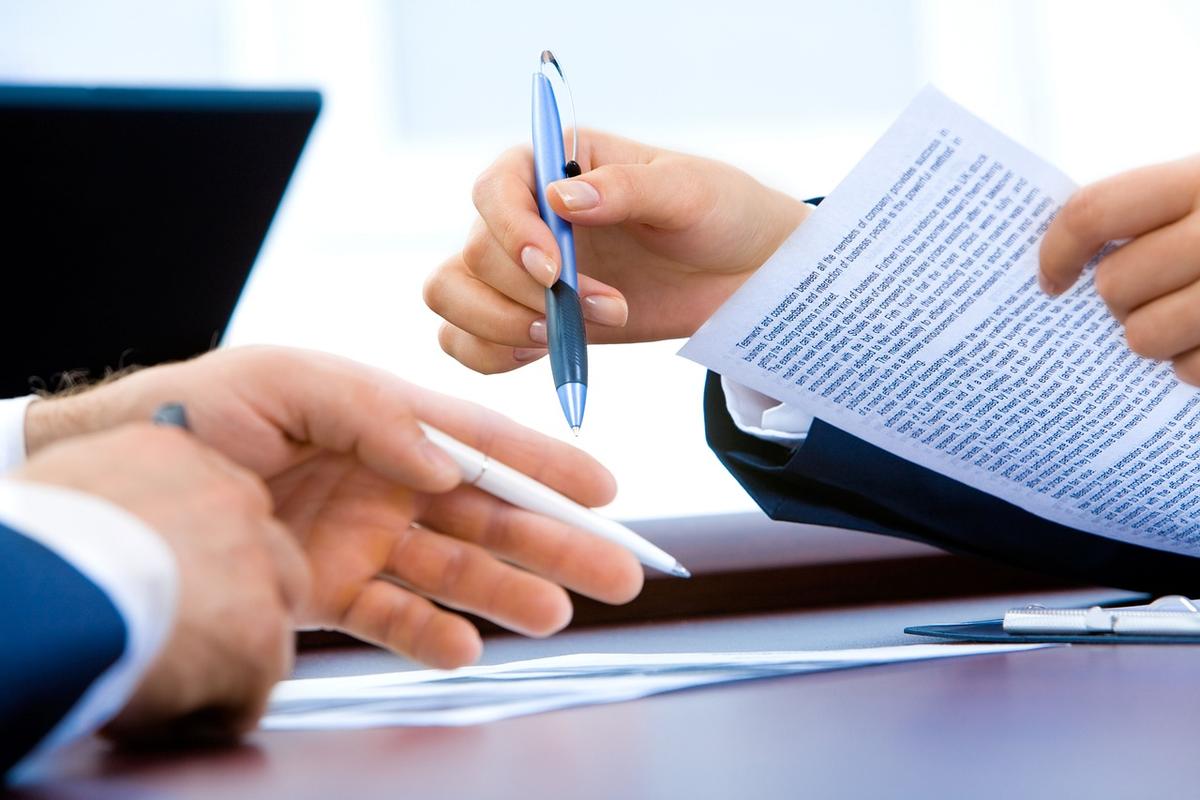 Deux personnes examinent des documents papier et numériques à un bureau professionnel
