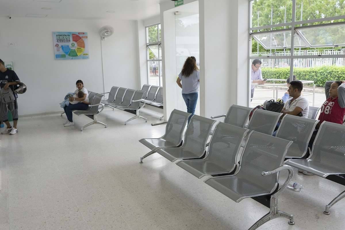 Salle d'attente avec chaises métalliques et personnes en attente