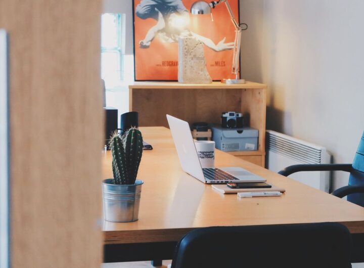 Un bureau avec ordinateur, cactus, chaise et tableau mural